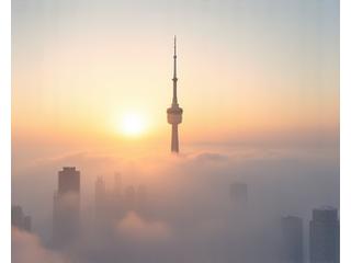 CN Tower piercing through spring morning fog, with city partially obscured.